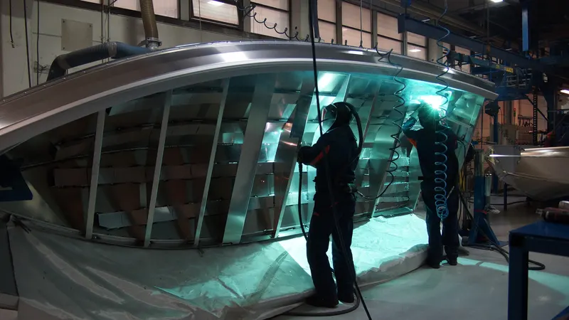 Deux soudeurs travaillant sur la coque en aluminium d'un bateau dans un hall de fabrication