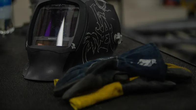 Gants de soudeur posés sur un établi à côté d'un masque de soudage à cristaux liquides