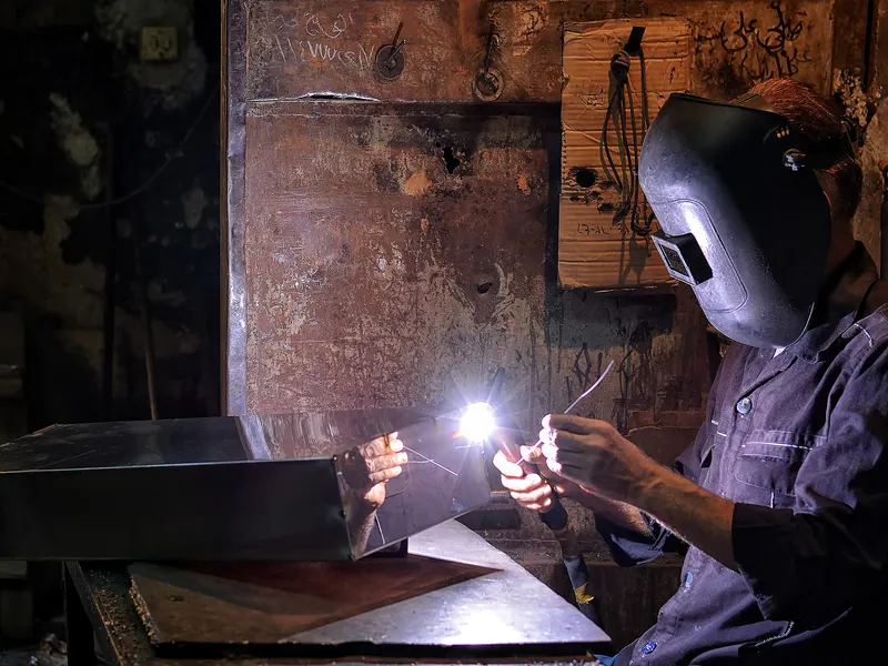 Soudeur professionnel casqué au travail sur une tôle dans un atelier de métallerie