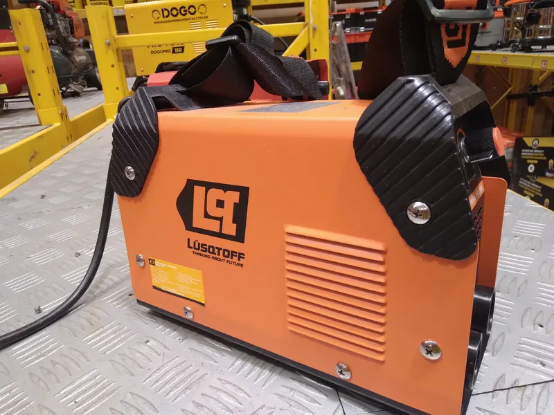Poste à souder inverter orange posé sur une tôle larmée dans un atelier