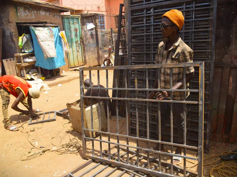 Grille de fenêtre en fer soudée posée debout dans un atelier de ferronnerie en plein air